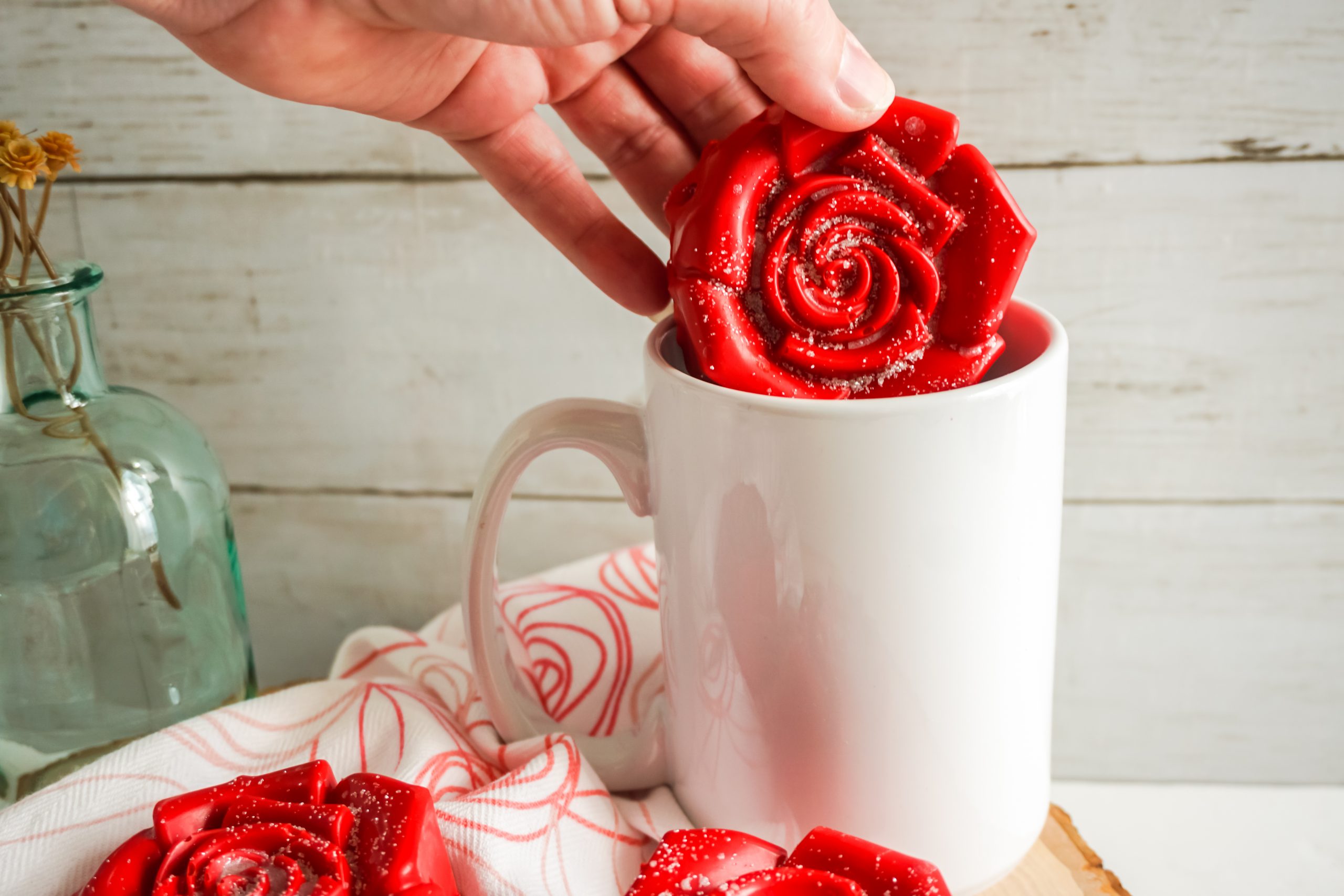 a red rose pop rocks hot cocoa bomb being put into a mug