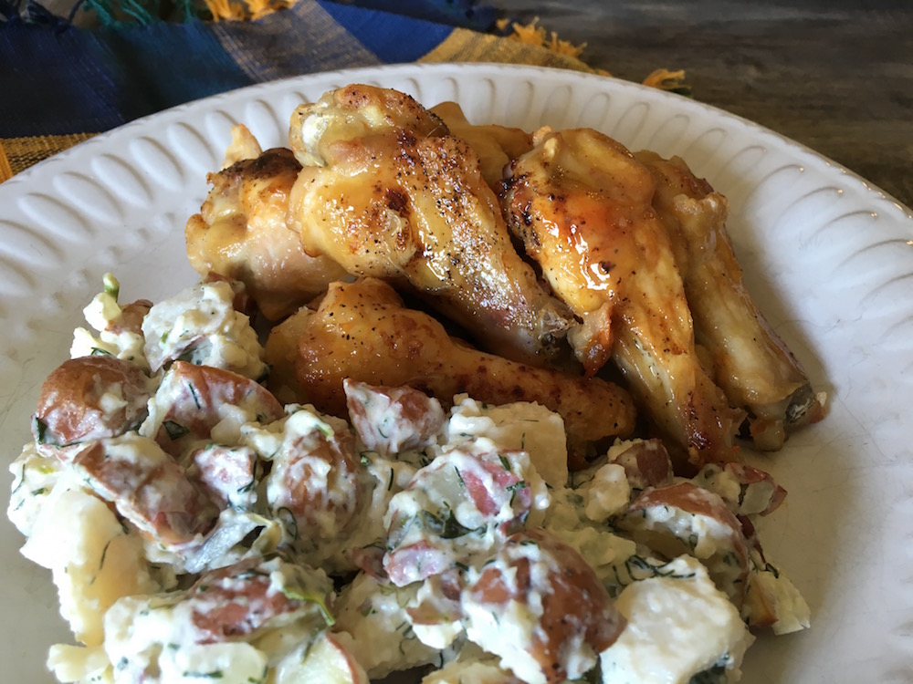 creamy red potato salad with fresh herbs on a plate with pieces of grilled chicken