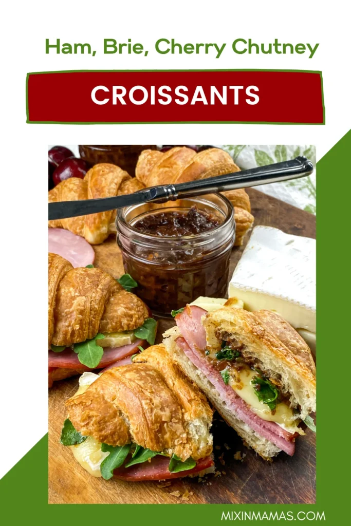 Pinterest pin showing a sliced ham, Brie, cherry chutney, and arugula croissant sandwich with fresh ingredients in the background.
