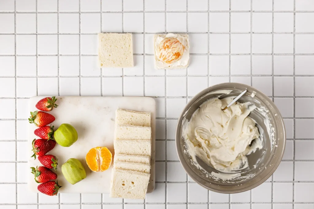 Orange slice placed on whipped cream-covered bread for fruit sandwich filling.