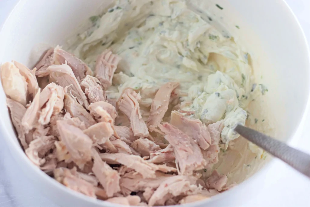 Shredded chicken being added to the cream cheese mixture.