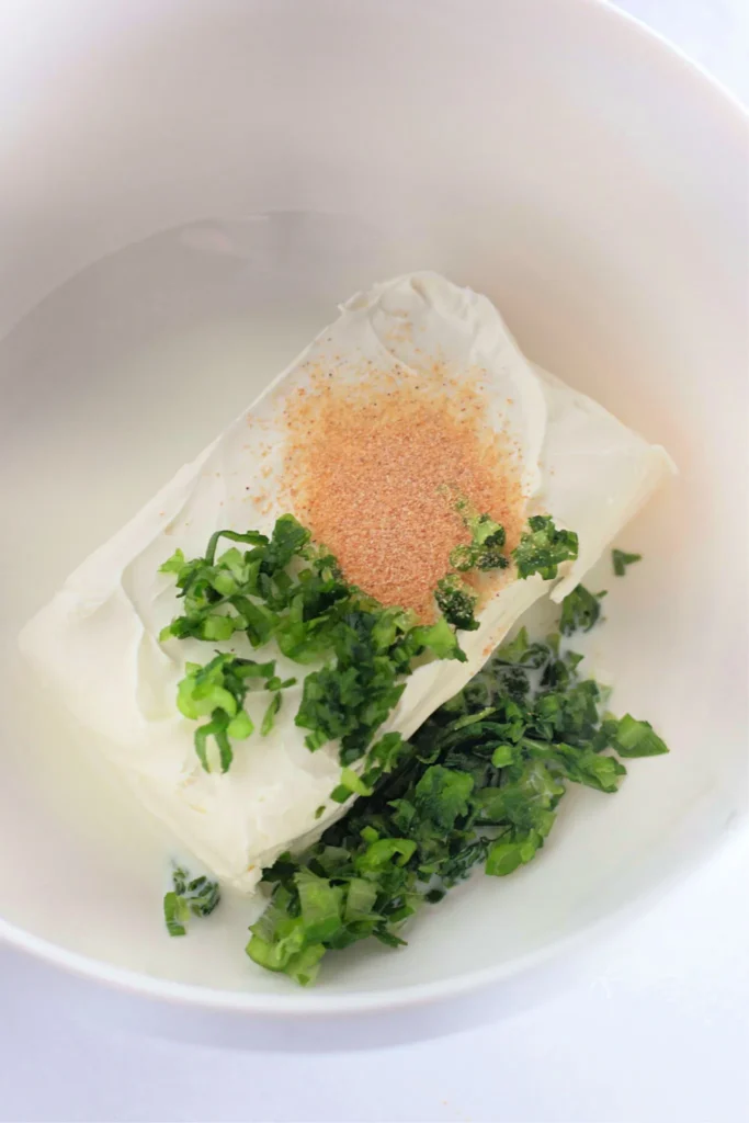 Cream cheese, garlic powder, milk, and green onions in a bowl ready to mix.