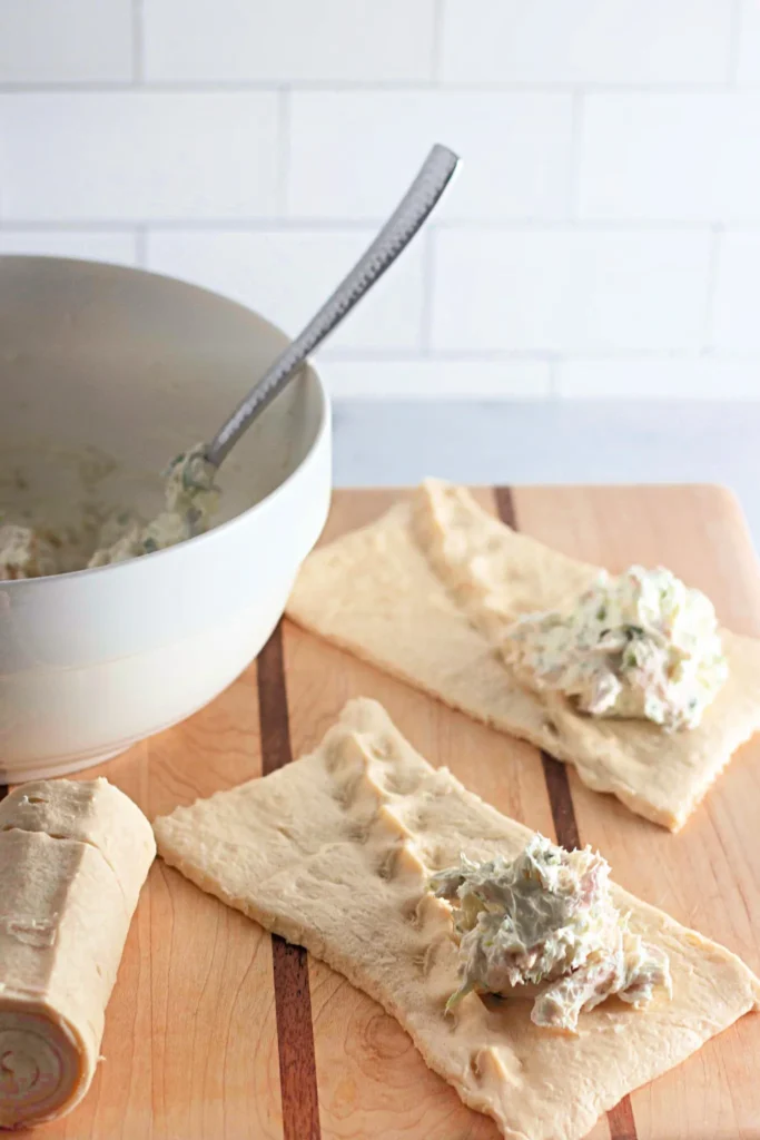 Crescent roll dough rectangles with creamy chicken filling spooned in the center.