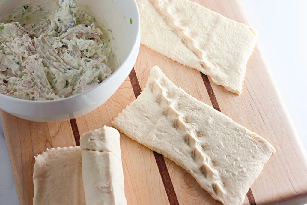 Rectangles of crescent roll dough laid out on a cutting board.