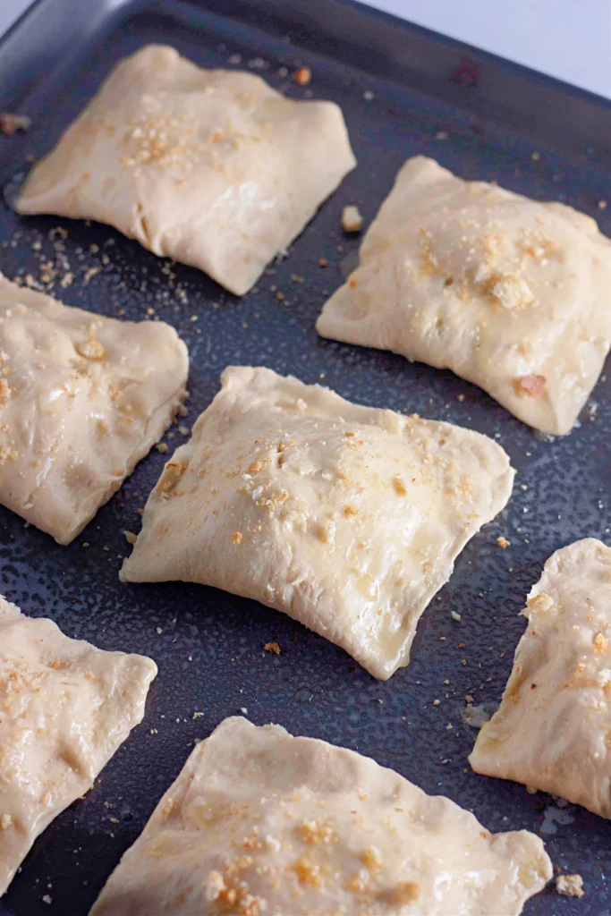 Unbaked crescent pockets brushed with butter and sprinkled with croutons.