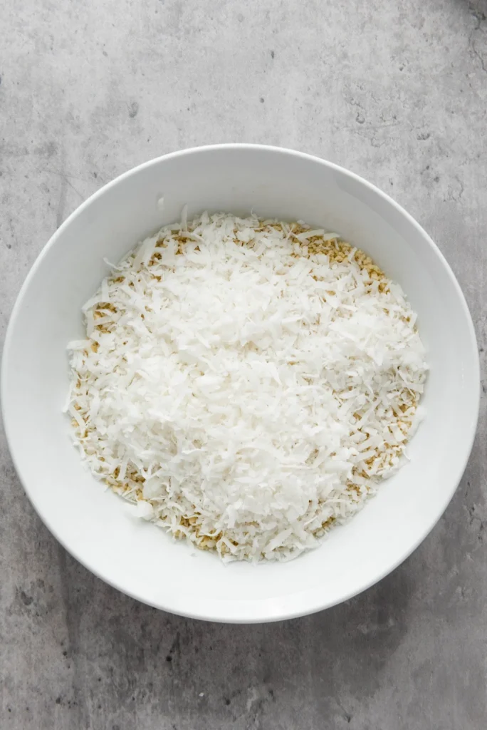 Shredded coconut added to panko breadcrumbs in a bowl.