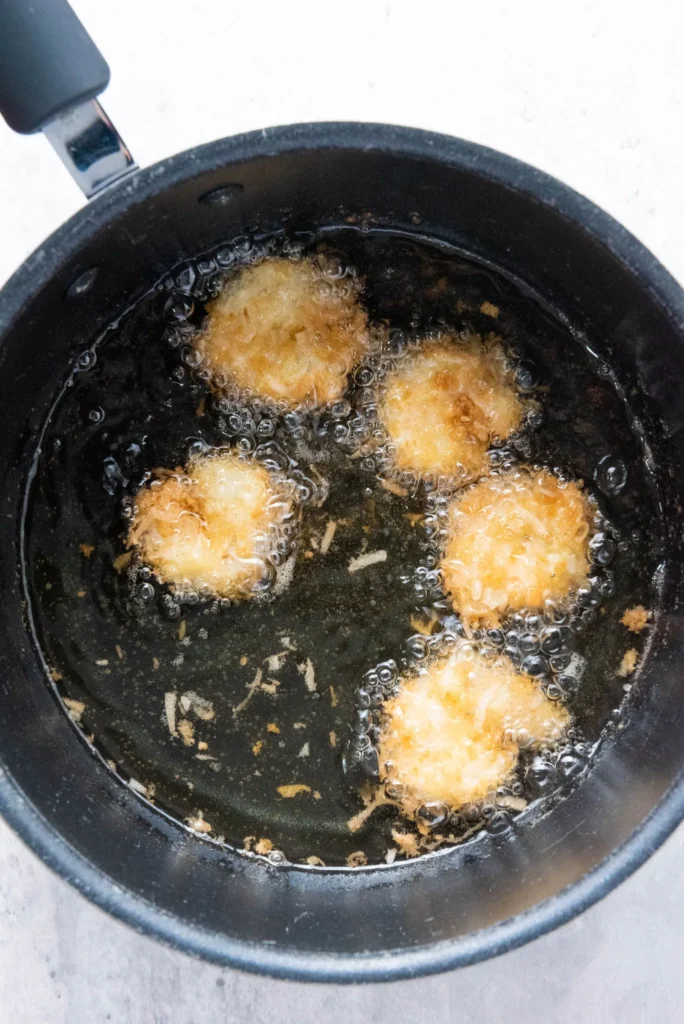 Shrimp turning golden brown as they fry in bubbling oil.