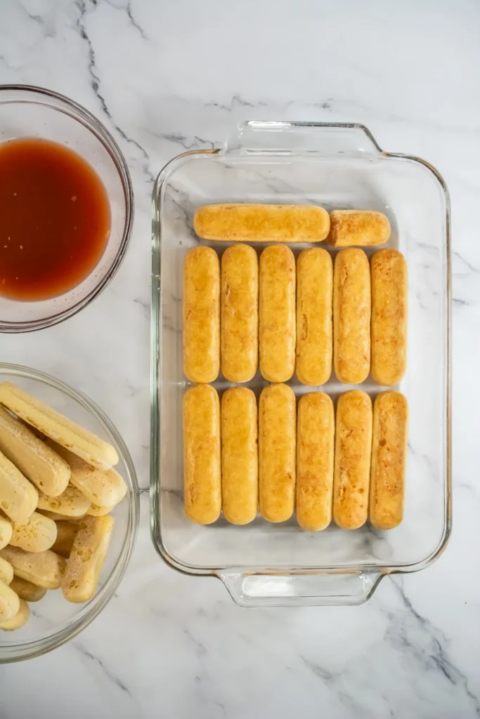 Ladyfinger cookies dipped in berry juice and layered in a 13x9 baking dish.
