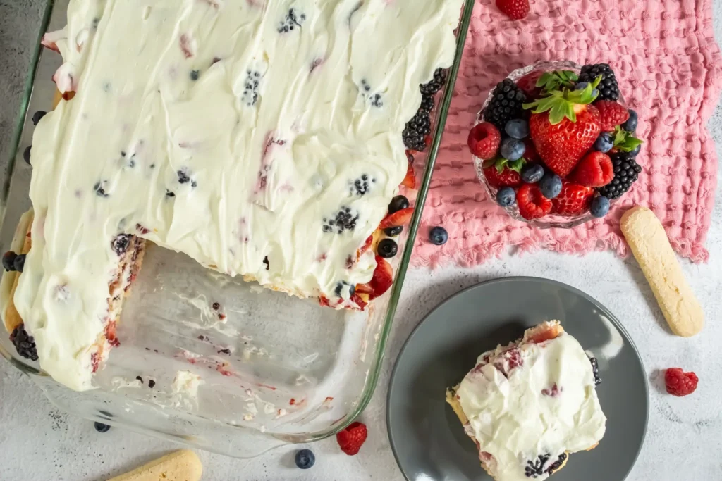 Pan of tiramisu with a portion removed, slice served on plate nearby.