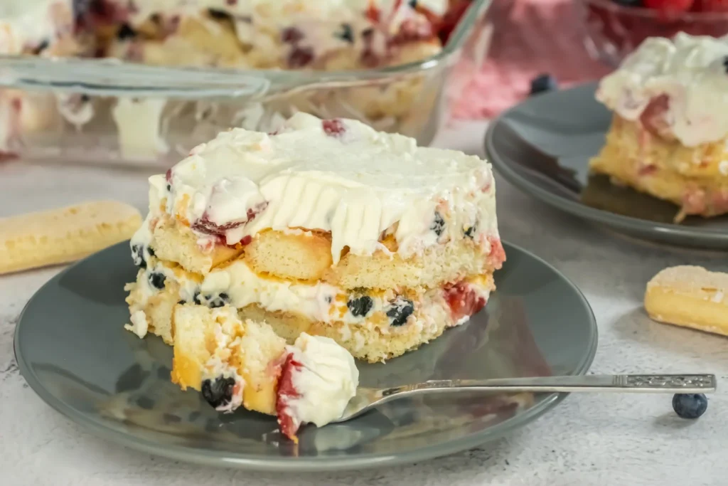 Slice of tiramisu on plate with a bite taken out, fork resting nearby.
