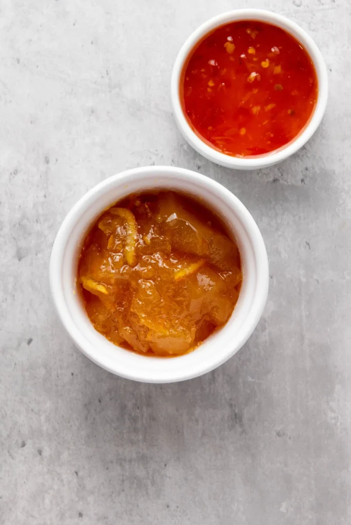 Small white bowls filled with orange marmalade and chili dipping sauce.