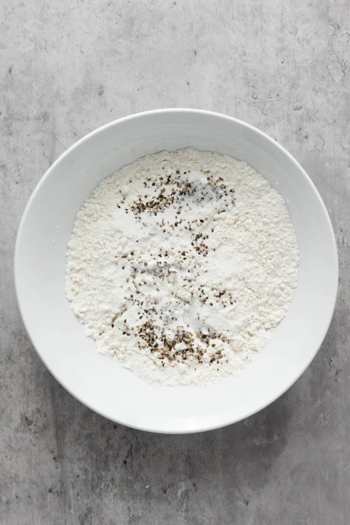 Flour mixed with salt and pepper in a white bowl.