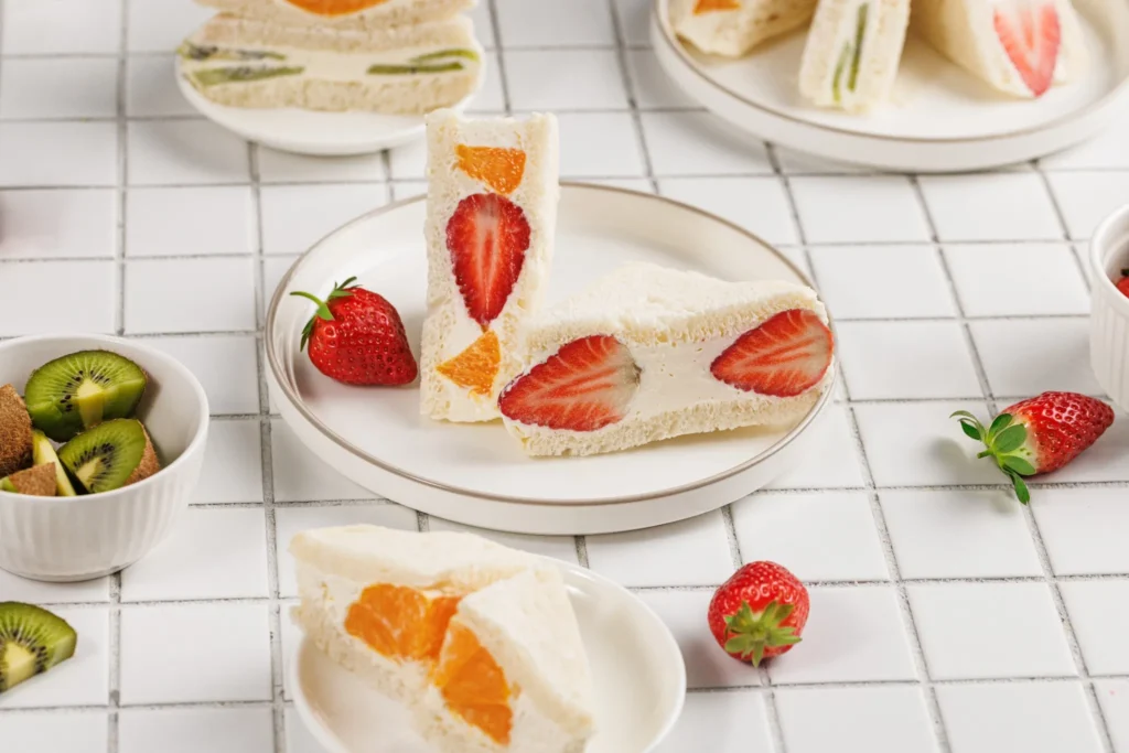 Cross-section of Japanese fruit sando showing strawberries and oranges in whipped cream filling.