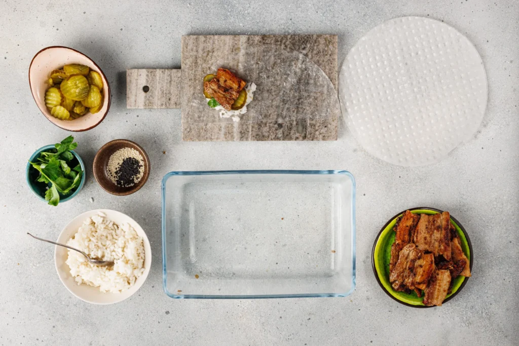 Cooked, caramelized pork belly added into rice paper wrapper with rice, cucumbers, and cilantro.