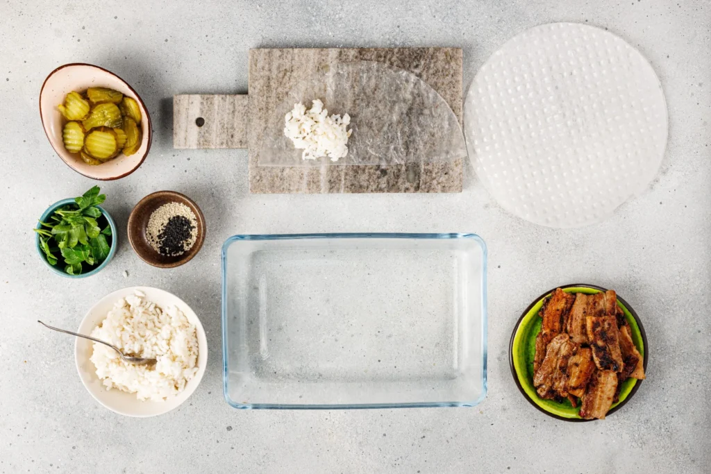 Step-by-step assembly showing rice paper wrapper with rice placed inside for spicy pork belly hand roll.