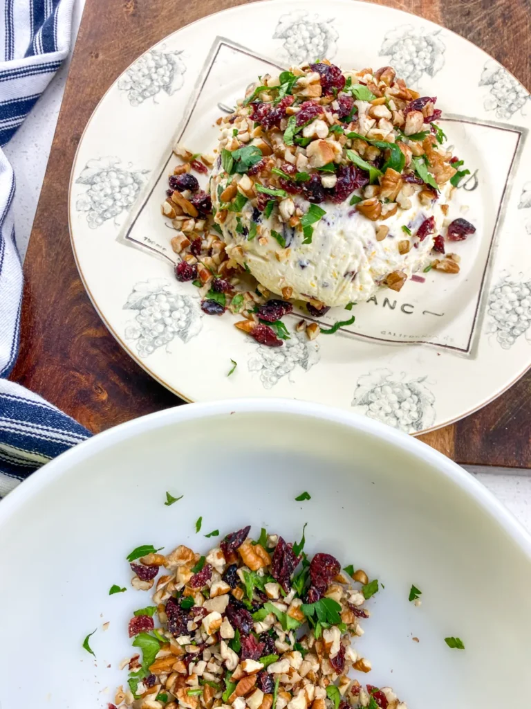 Pressing cranberry pecan mixture onto the outside of the cheese ball to cover completely.