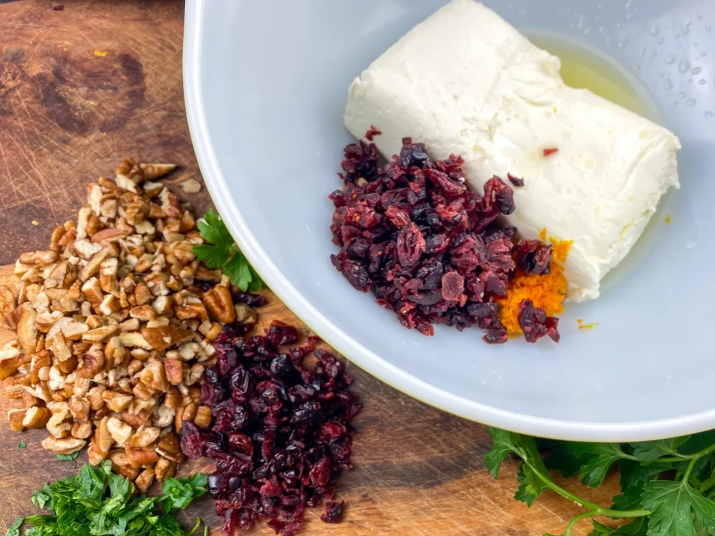 Mixing chopped dried cranberries into the orange zest and cream cheese mixture.