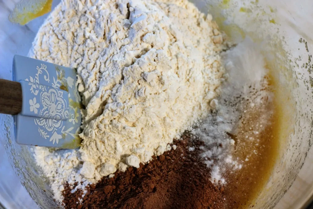 Cocoa powder, flour, and baking soda added on top of the wet mixture in the bowl before stirring.