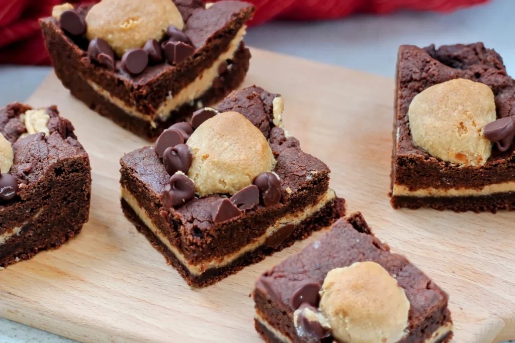 Overhead view of several Buckeye Cookie Bars arranged on a wooden board with a red cloth in the background.