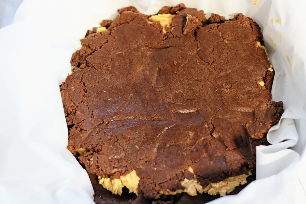 The top chocolate cookie dough layer pressed and smoothed evenly in the pan.