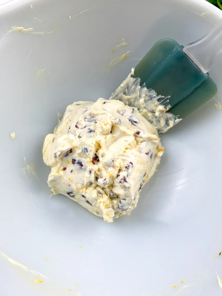 Orange cranberry cream cheese mixture being folded together with a spatula until smooth.