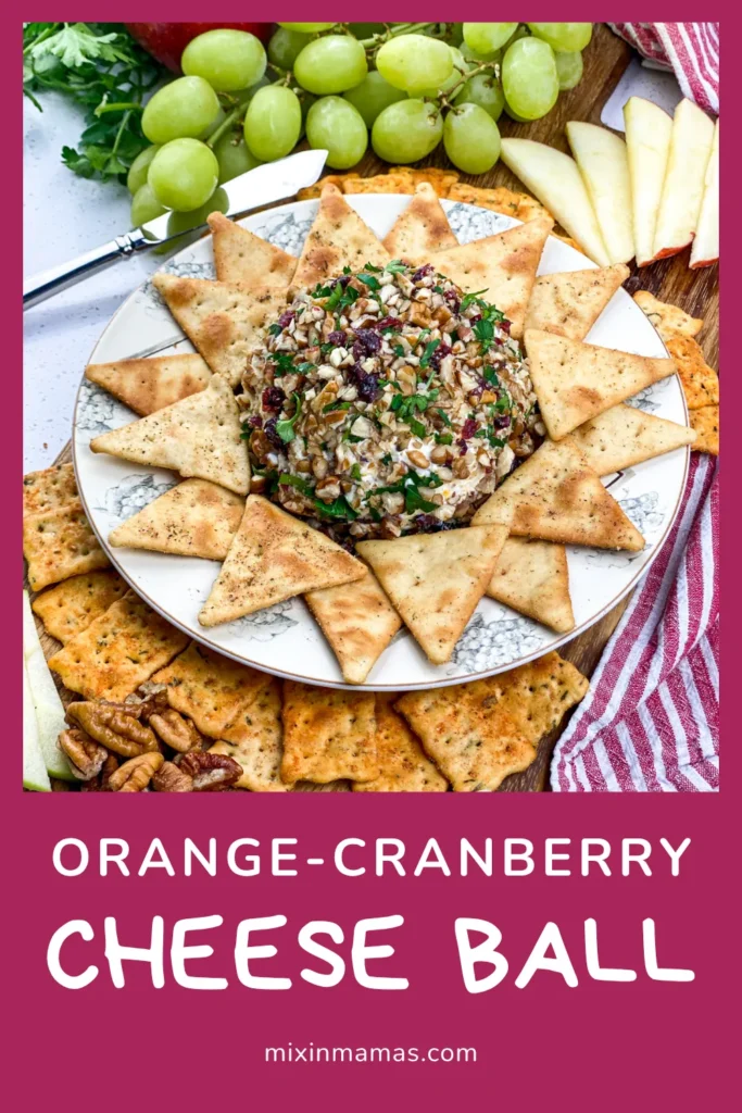 Festive orange cranberry cheese ball appetizer with crackers and fruit on a serving board, perfect for holidays.