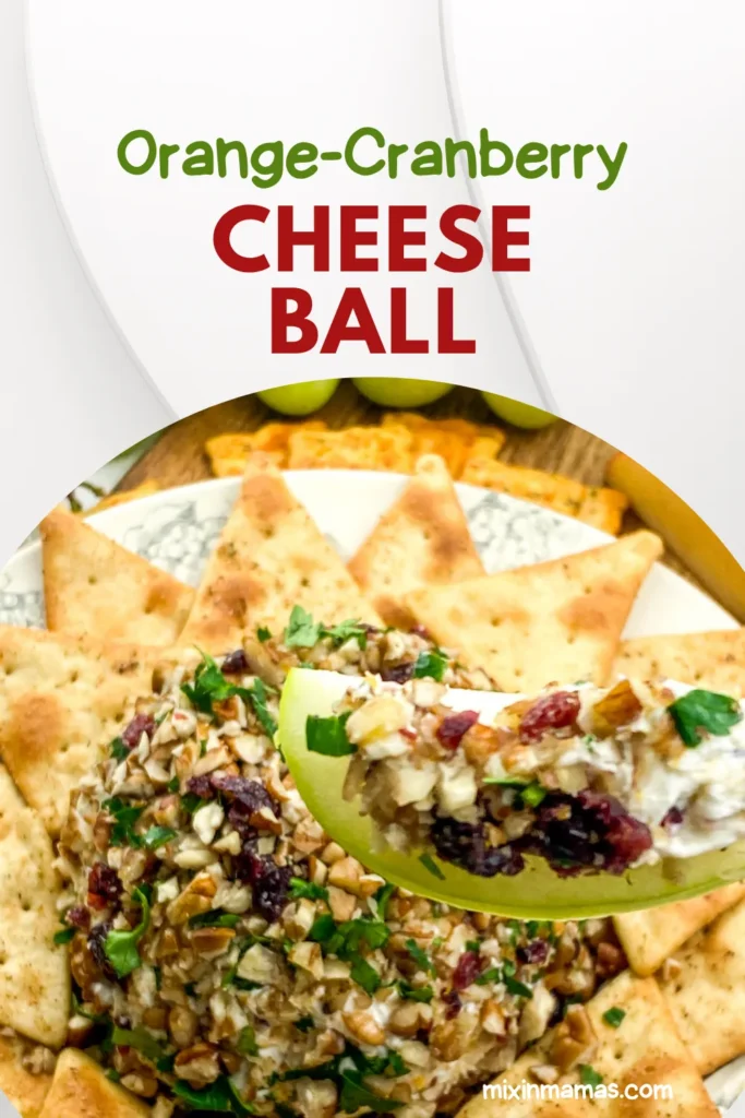 Close-up of orange cranberry cheese ball with apple slice scoop, surrounded by crackers and grapes, labeled with recipe title.
