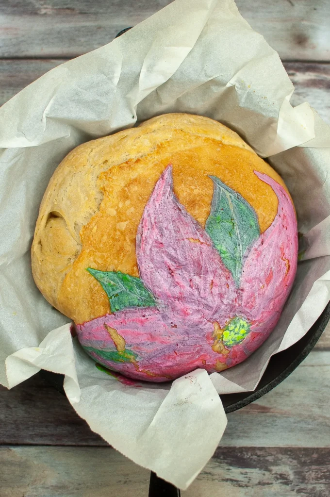 Loaf fresh from the oven, showing softened baked-in poinsettia design with golden crust.