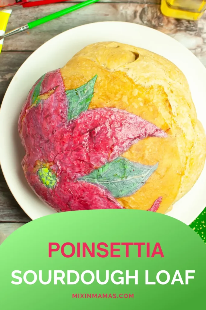 Holiday sourdough loaf decorated with a red poinsettia flower, shown on a serving plate.