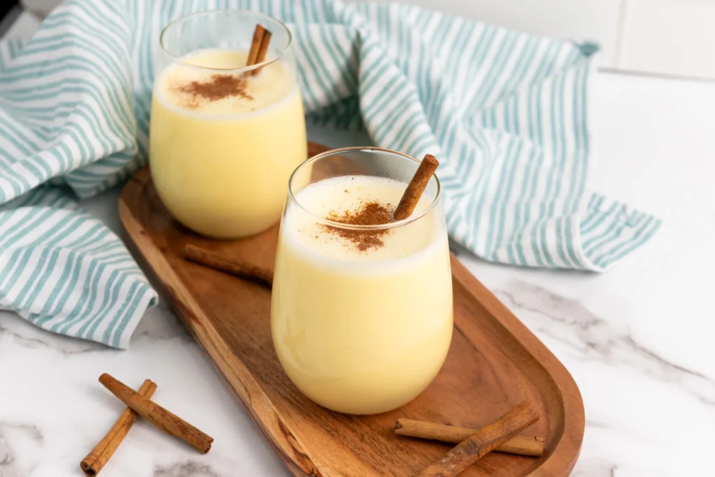 Cinnamon sprinkled into warm homemade eggnog