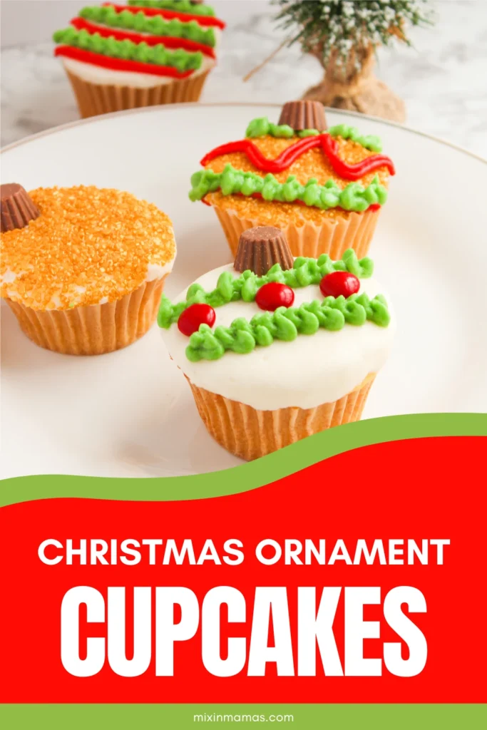 Christmas ornament cupcakes decorated with green and red frosting, sanding sugar, and mini Reese’s cups displayed on a white plate