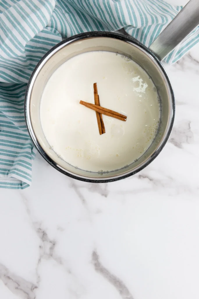 Cinnamon sticks infusing warm milk and cream for eggnog