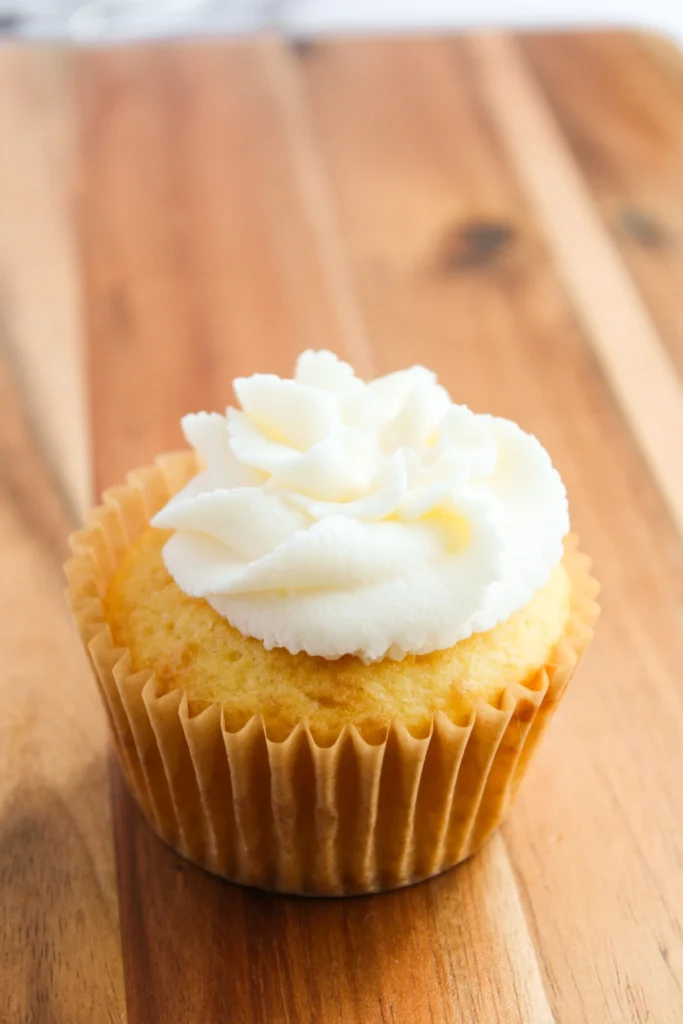 Vanilla cupcake topped with a smooth layer of plain buttercream frosting