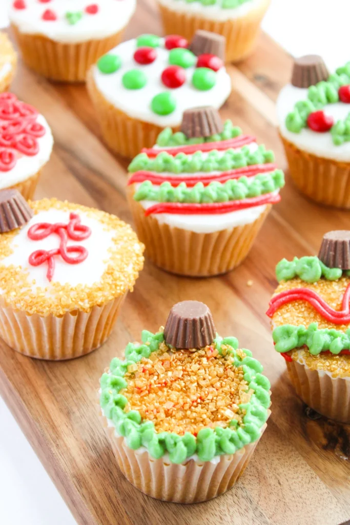 Close-up of decorated Christmas ornament cupcakes with sanding sugar and Reese’s tops