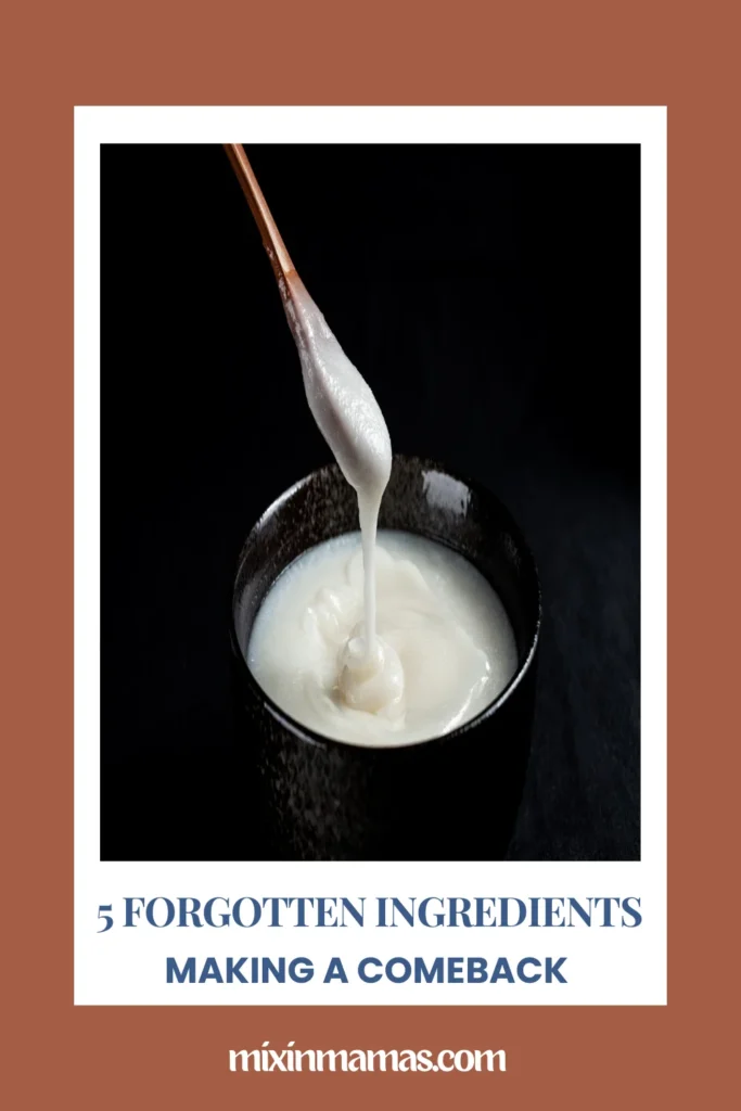 Melted lard or rendered fat dripping from a spoon into a dark bowl with text reading “5 Forgotten Ingredients Making a Comeback”