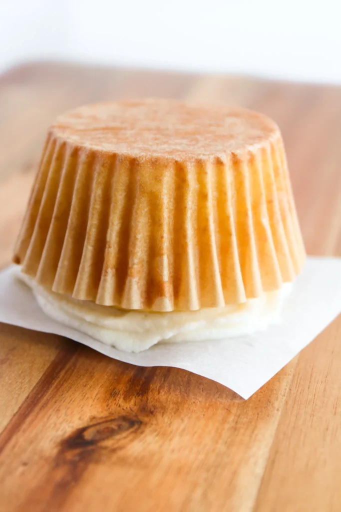 Flattening a cupcake top using parchment paper to create an ornament shape