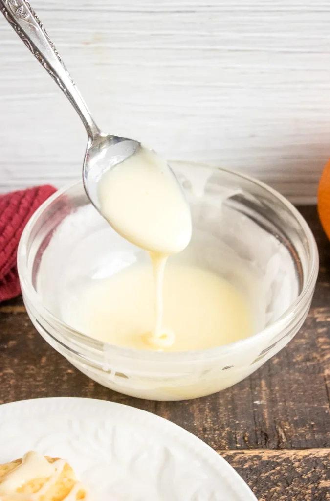 Fresh orange glaze being stirred in a glass bowl