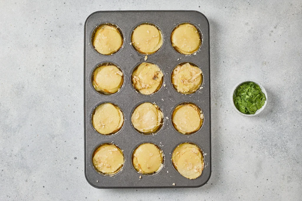 Parmesan garlic potato stacks assembled in a muffin tin before baking