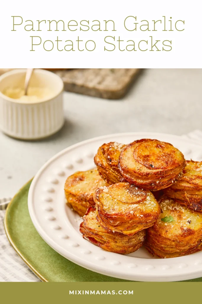 Parmesan garlic potato stacks stacked on a plate with crispy edges and fresh herb garnish