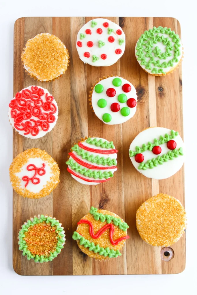 Overhead view of decorated Christmas ornament cupcakes with red and green frosting designs