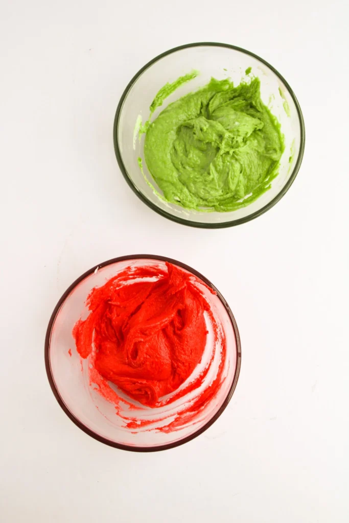 Green and red buttercream frosting in separate bowls for decorating ornament cupcakes