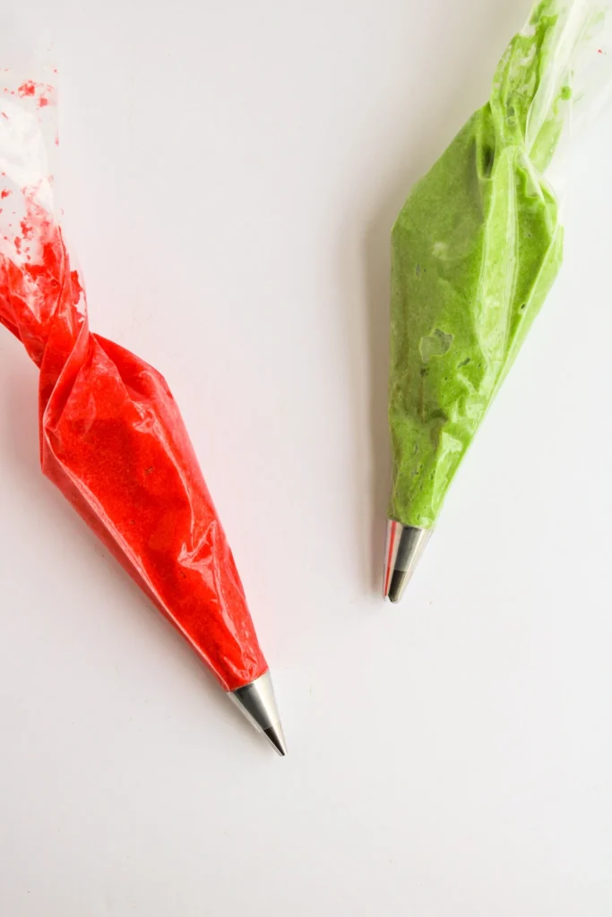 Red and green frosting in piping bags fitted with metal tips for decorating Christmas cupcakes