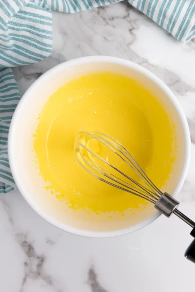 Smooth, pale yellow egg yolk and sugar mixture whisked for eggnog