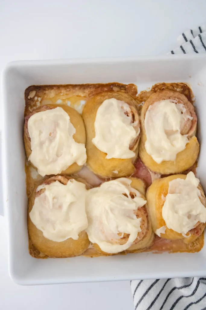 Strawberry sweet rolls topped with cream cheese glaze in a baking dish