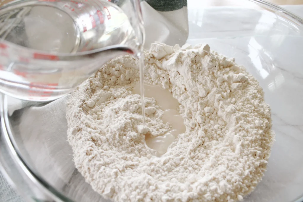 Water being poured into dry ingredients for no-knead bread dough