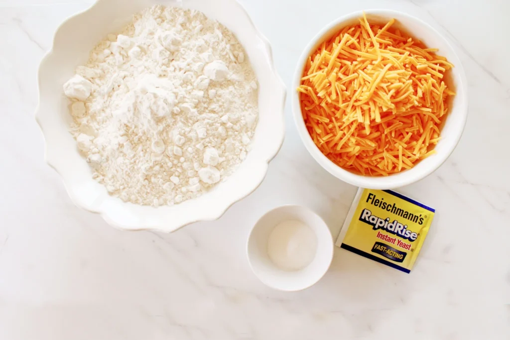 Dry ingredients for no-knead cheddar bread in a glass bowl