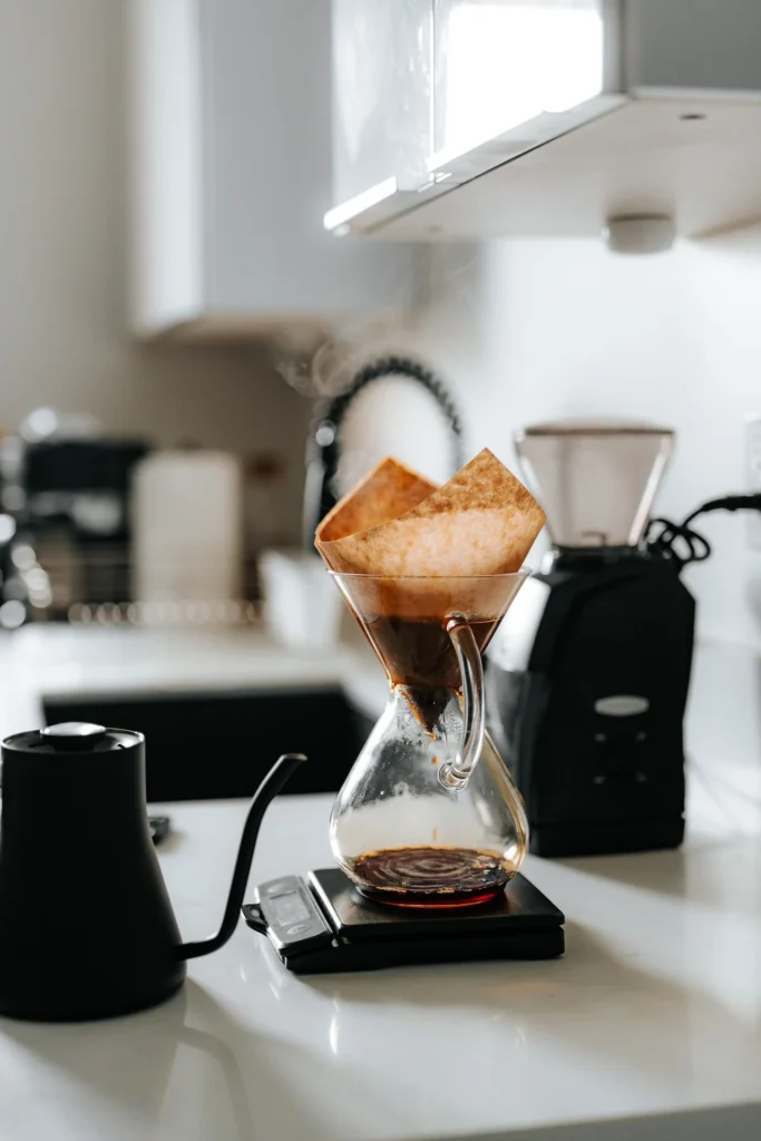 Pour-over coffee brewing in a glass dripper with a kettle nearby