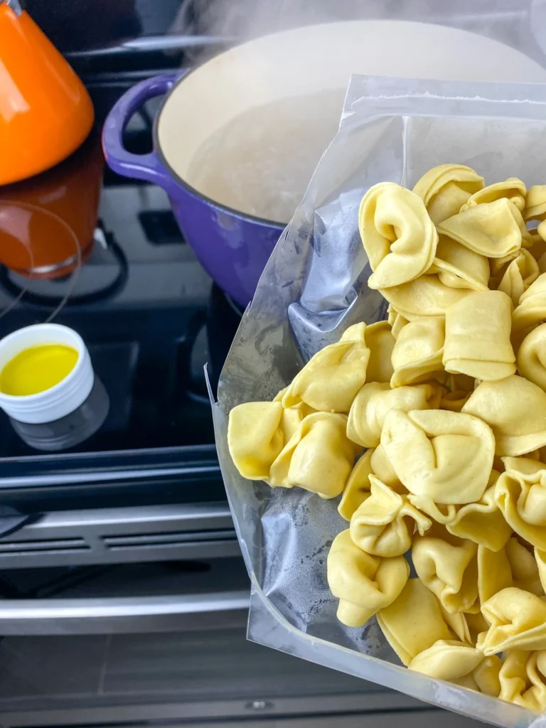 Fresh cheese tortellini being added to a pot of boiling water.