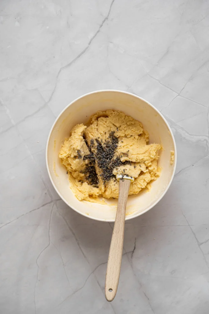 Culinary lavender being added to lavender cookie dough before mixing.