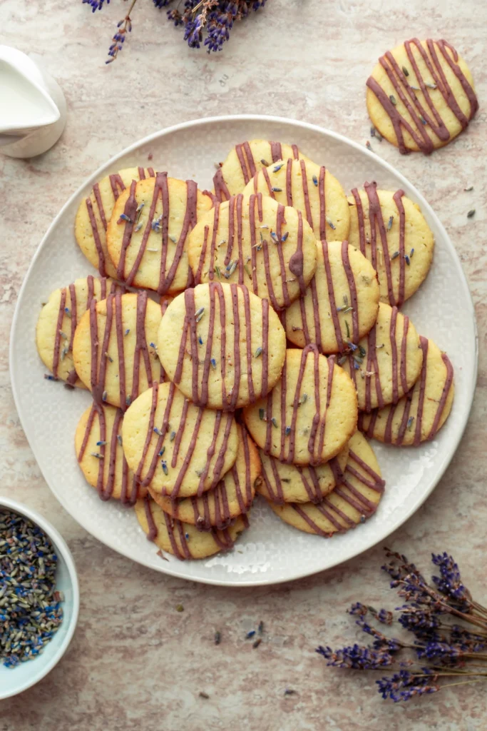 Lavender cookies with purple icing drizzled on top arranged on a serving platter.